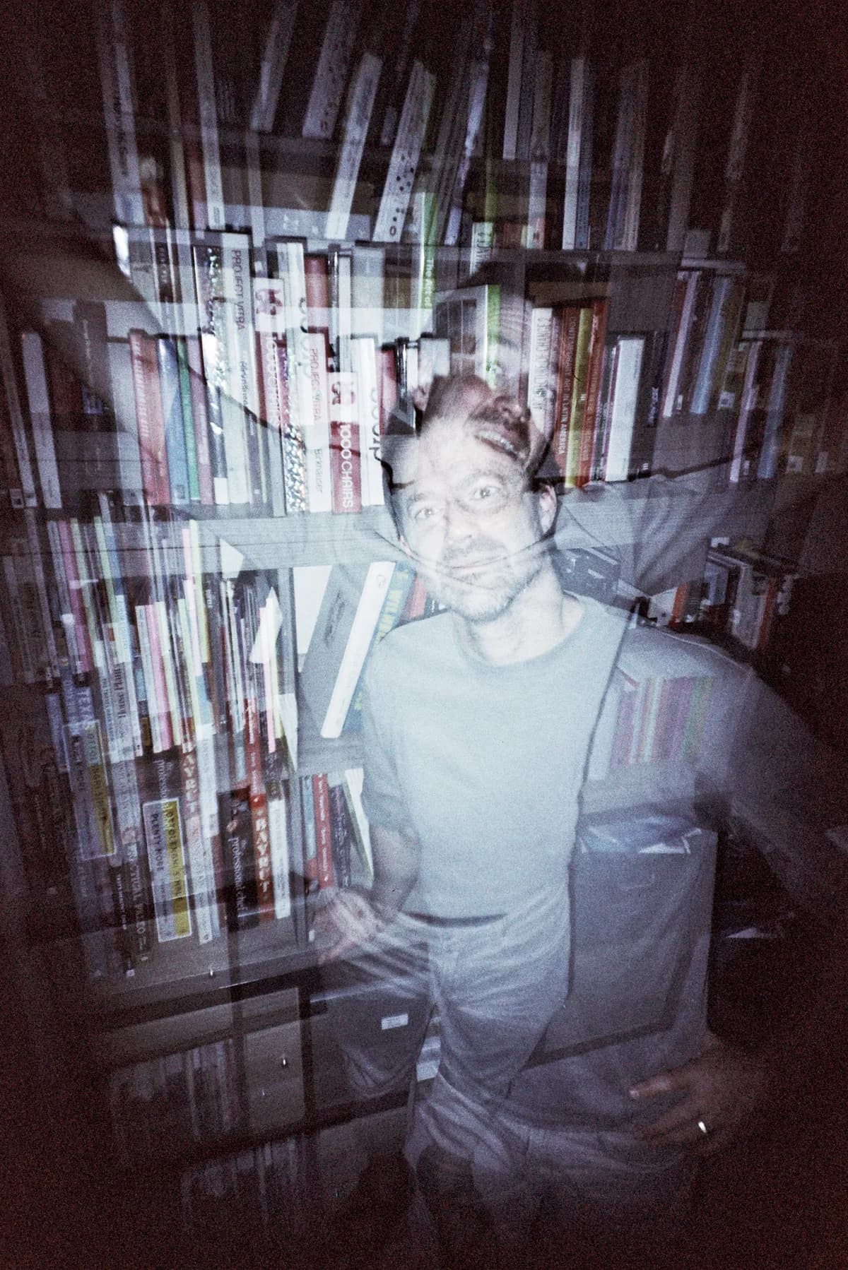 Motion-blurred portrait against a wall of books and media