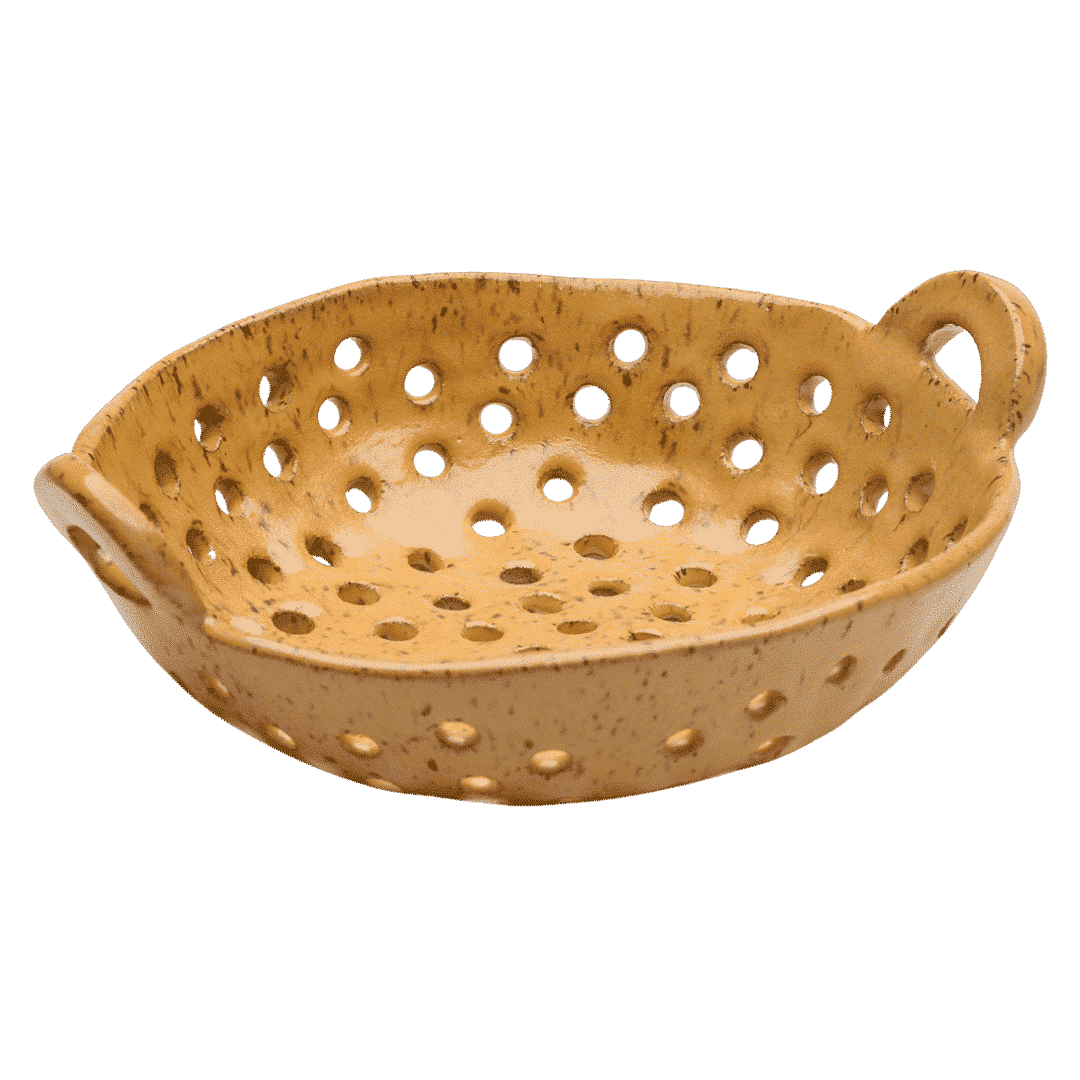 Handbuilt ceramic pasta colander in ochre yellow glaze with patterned drainage holes and curved handles, shown against white background